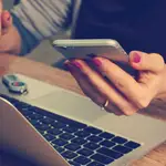 Una persona utiliza un ordenador y un móvil