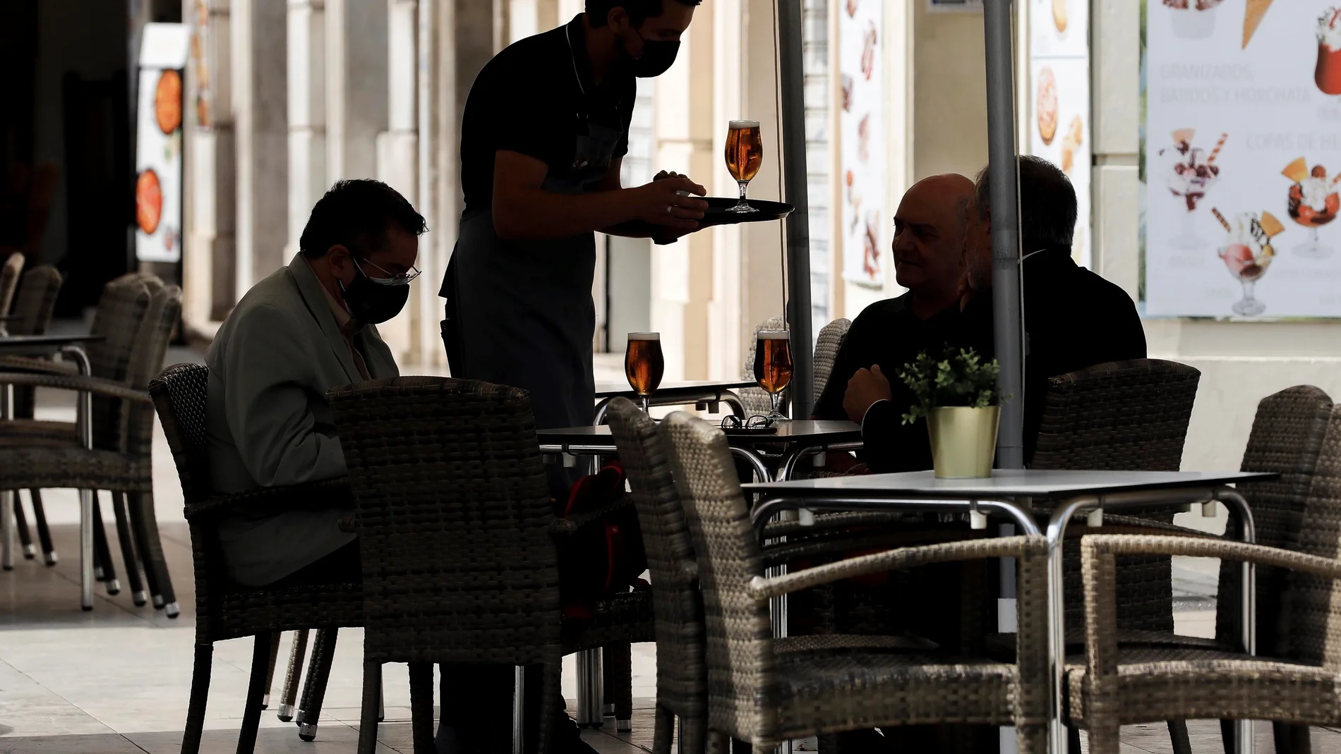 Un camarero atiende una mesa en una terraza