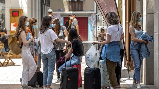 Varias turistas esperan junto a sus maletas frente al portal de un edificio del centro hist&oacute;rico de Valencia