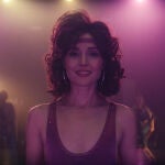 Sheila, interpretada por Rosa Byrne, en el centro de la imagen, hace negocio con cintas en pelos cardados y calentadores