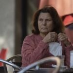 Una mujer en la terraza de un bar con la mascarilla en la mano