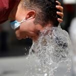 Una persona se refresca en una de la fuentes del centro de Córdoba