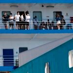 Varias personas saludan desde el ferry en el que viajaban 118 estudiantes que habían sido confinados en un hotel de Mallorca