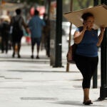 Una mujer se protege del sol con una caja de cartón