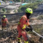 Bomberos trabajan en el incendio. Al fondo de la imagen se ve la proximidad del parque acuático