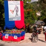 AME3457. PUERTO PRÍNCIPE (HAITÍ), 19/07/2021.- Personas pasan hoy junto a un altar en homenaje al asesinado expresidente Jovenel Moise, en Puerto Príncipe (Haití). Haití tendrá un nuevo primer ministro al cumplirse trece días del asesinato del presidente Jovenel Moise, quien había designado a Ariel Henry para el cargo, del que no llegó a tomar posesión oficialmente antes del magnicidio. Desde entonces, Claude Joseph ha dirigido el país como primer ministro interino y mañana cederá el cargo a Henry, poniendo así fin a una pugna protagonizada por ambos y por el presidente del Senado, Lambert, tercer aspirante en discordia a la Primatura. EFE/ Orlando Barría
