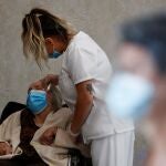 Una trabajadora sanitaria de una residencia de la Comunidad de Madrid atiende a Carmen, de 89 años