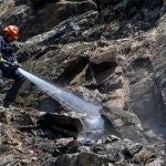 Un bombero trabaja en la extinción de un foco de fuego en el incendio del pantano de San Juan