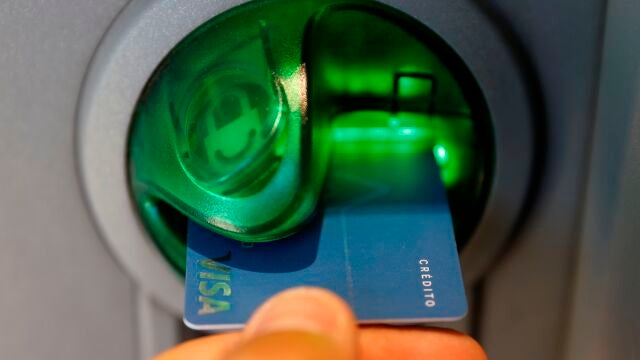 Una persona saca dinero de un cajero de una entidad bancaria