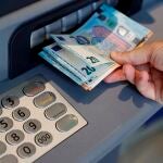 Una persona saca dinero de un cajero de una entidad bancaria