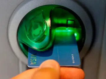 Una persona saca dinero de un cajero de una entidad bancaria Una persona saca dinero de un cajero de una entidad bancaria