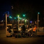 Varias personas en la terraza de un bar, frente a la playa de la Barceloneta