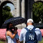 Una pareja conversa ante la Puerta de Alcalá de Madrid