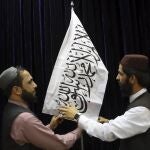 Oficiales talibanes arreglan la bandera antes de una rueda de prensa en Kabul
