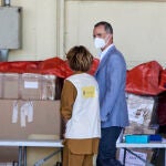 El Rey Felipe VI conversa con una cooperante a su llegada al hangar para visitar el dispositivo provisional en Torrejón de Ardoz
