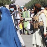 Un talibán apunta a la espalda de una mujer con burka en los alrededores del aeropuerto de Kabul la semana pasada