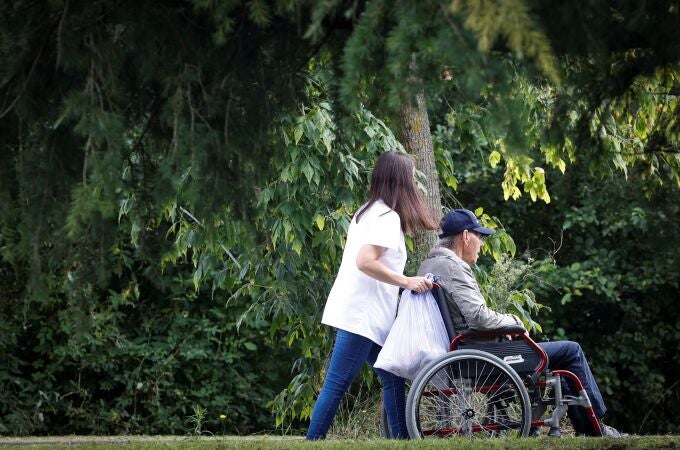Una mujer pasea con un hombre en silla de ruedas en San Sebastián