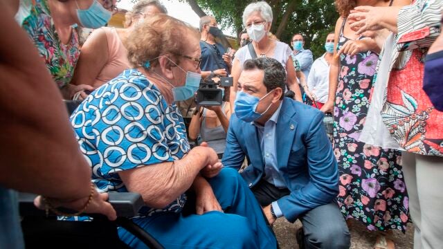 El presidente de la Junta de Andalucía, Juanma Moreno, saluda a una vecina de la barriada de La Asunción, en Jerez de la Frontera (Cádiz), este lunes