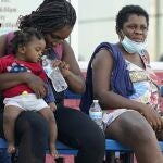 Migrants, mostly from Haiti, wait for a bus after they were processed and released after spending time at a makeshift camp near the International Bridge, Sunday, Sept. 19, 2021, in Del Rio, Texas. President Joe Biden's administration is nearing a final plan to expel many of the thousands of Haitian migrants who have suddenly crossed into a Texas border city from Mexico and to fly them back to their Caribbean homeland. (AP Photo/Eric Gay)