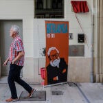 Un hombre camina frente a un 'roll-up' y una placa-homenaje a homenaje a Luis García Berlanga, aún sin descubrir, con motivo del Día del Cine Español06/10/2021