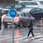 Una mujer cruza un paso de peatones bajo una intensa tormenta en Murcia