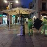 Trabajadores municipales retiran mesas de una terraza.