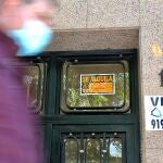 Un hombre pasa por delante de dos anuncios de viviendas en venta y alquiler