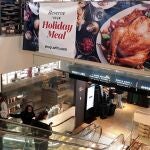 Personas pasan frente a un cartel de ofertas de pavo por el Día de Acción de Gracias, el 23 de noviembre de 2021 en un supermercado de Nueva York (EE.UU)