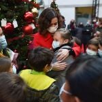 La presidenta de la Comunidad de Madrid, Isabel Díaz Ayuso, abraza a una niña en uno de los árboles del Bosque de los Deseos, ayer en Madrid