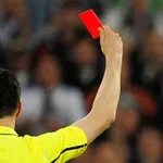 Un árbitro muestra una tarjeta roja
