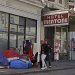 Los peatones caminan por el borde de una acera para evitar tiendas de campaña y sacos de dormir, el 13 de abril de 2020, en la zona del Tenderloin de San Francisco