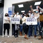 Trabajadores y vecinos de la administración número 3 de Manises, sita en la calle Maestro Guilen, celebran la venta de dos de los quintos premios, el número 92.052 y el 70.316