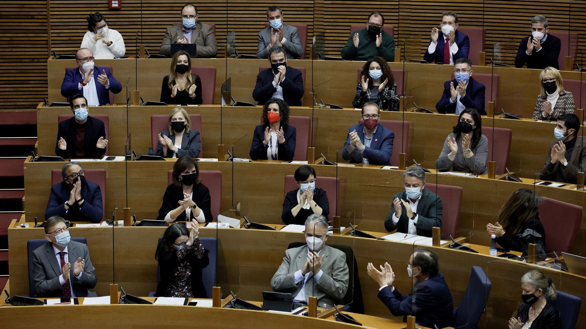 El president de la Generalitat, Ximo Puig (i), junto a diputados del grupo parlamentario socialista, aplauden tras la aprobación de la ley de acompañamiento a los presupuestos, durante el pleno de Les Corts Valencianes donde se aprueban los Presupuestos de la Generalitat para 2022, que crecen un 9,1 % respecto a las cuentas del actual ejercicio hasta alcanzar los 27.967,5 millones de euros. EFE/Biel Aliño