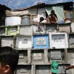 A father and son spruce up the crypt of the departed loved one at a public cemetery at suburban Navotas north of Manila, Philippines.