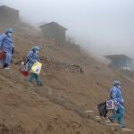 FILE - Healthcare workers carry coolers filled with doses of the Pfizer COVID-19 vaccine during a door-to-door vaccination campaign in the Villa Maria del Triunfo district on the outskirts of Lima, Peru, Nov. 16, 2021. Peru confirmed on Tuesday, Jan. 4, 2022, the start of a third wave of new coronavirus infections. (AP Photo/Guadalupe Pardo, File)