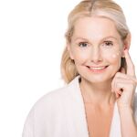 Happy mature woman applying cosmetic cream