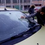 Un mujer retira el hielo de su coche por las fuertes heladas sufridas