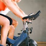 Three people working out on a stationary bicycle in the gym