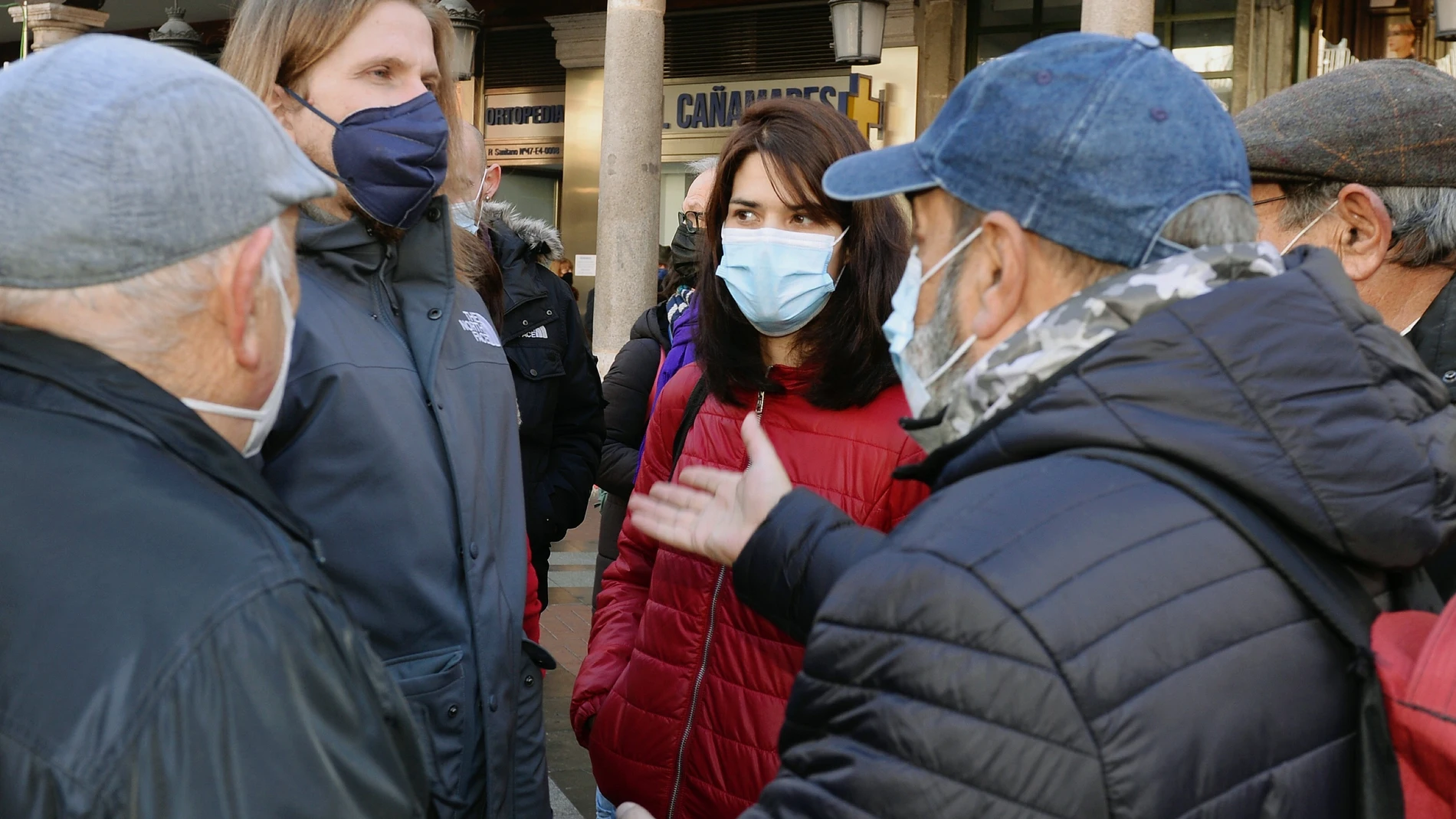 Pablo Fernández (i), candidato de Unidas Podemos a la Presidencia de Castilla y León, e Isa Serra (c), portavoz de la formación política, conversan con un grupo de pensionistas este lunes en Valladolid