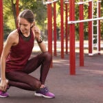 Joven con auriculares inalámbricos escuchando música en terreno deportivo