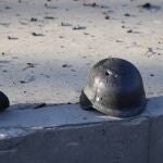 El casco de un soldado con un agujero de bala cerca de los escombros de camiones militares en llamas, en una calle de Kiev