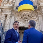 El presidente de la Junta de Andalucía, Juanma Moreno, y el resto de miembros del Consejo de Gobierno asisten a la colocación de la bandera nacional de Ucrania en la fachada principal del Palacio de San Telmo
