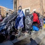 Varias personas hacen cola para recibir alimentos de la Fundación Madrina, en la plaza de San Amaro, en Madrid (España)