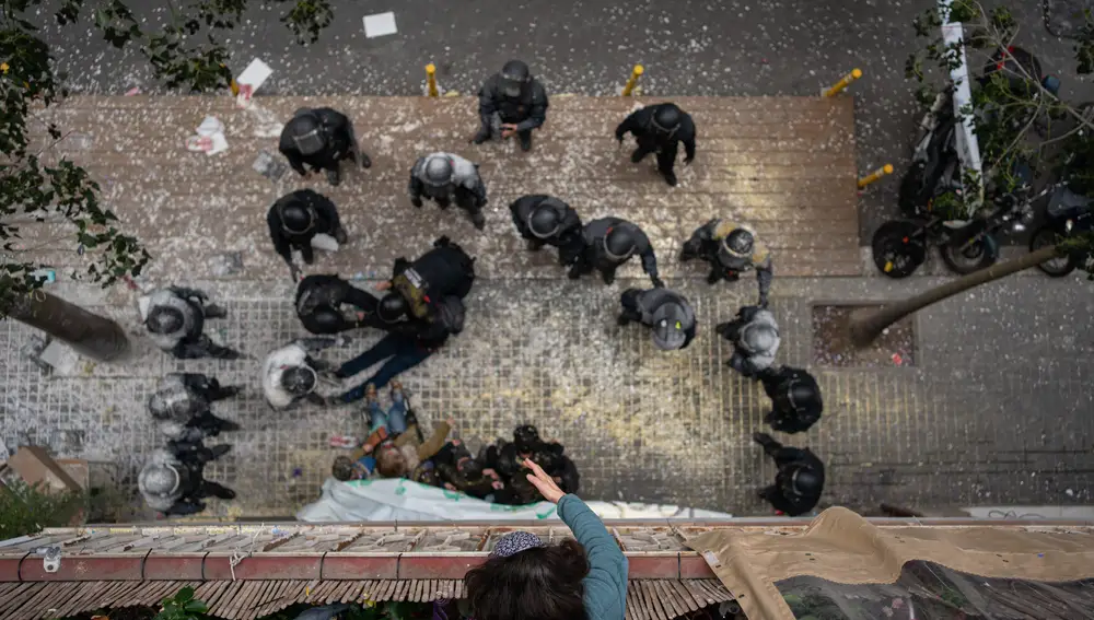 Plano cenital de los Mossos díEsquadra llenos de harina por parte de las personas que intentaron paralizar el desahucio de una familia por impago de alquiler en el barrio de Poble-Sec en diciembre