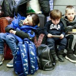 Niños ucranianos refugiados descansan sobre su equipaje tras llegar a la estación principal de tren de Cracovia