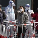Trabajadores hacen cola para la prueba de Covid fuera de un edificio de oficinas hoy lunes 14 de marzo de 2022 en Beijing