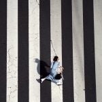 Una mujer con mascarilla vestida con un "kimono" corre por un paso de peatones en el distrito comercial de Ginza