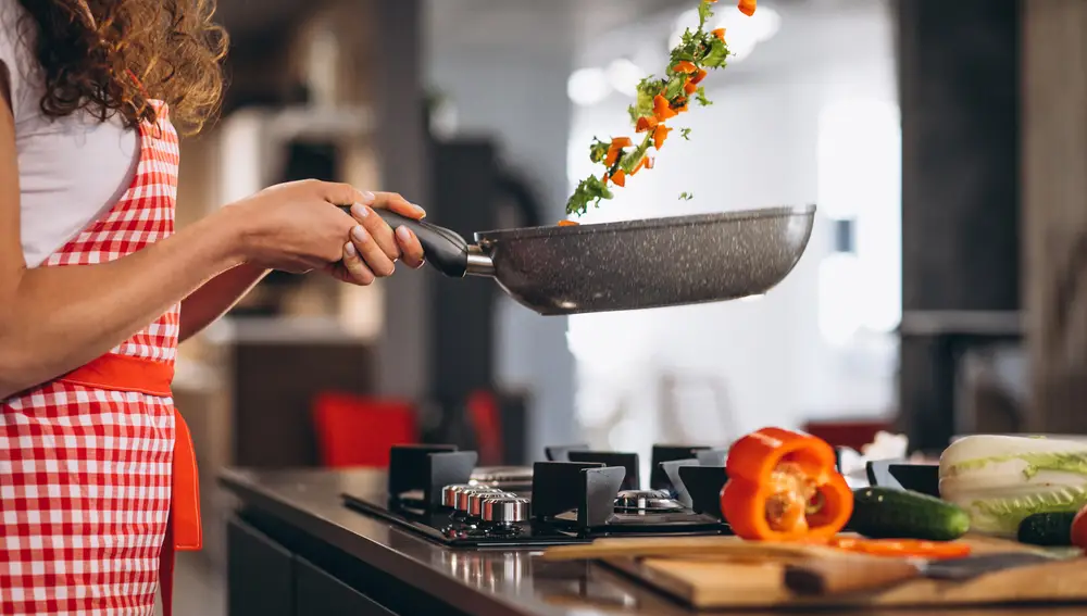 Mujer cocinando verduras en una sartén