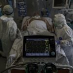 Personal sanitario totalmente protegido atiende a un paciente ingresado en la Unidad de Cuidados Intensivos del Hospital Infanta Sofía en San Sebastián de los Reyes (Madrid)