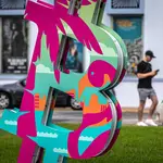 Una persona camina detrás de una "B" de bitcoin y blockchain en Miami